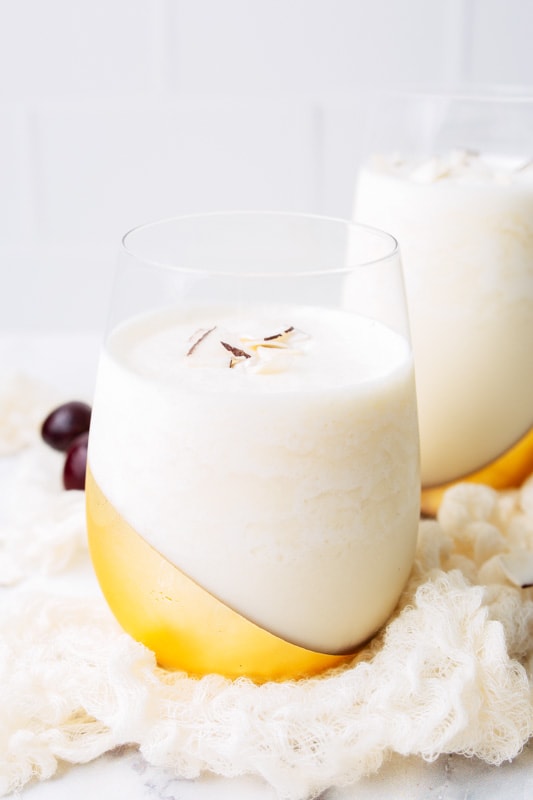pina colada in a glass topped with coconut