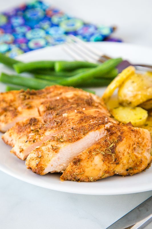 Cut up chicken breast on plate with green beans and potatoes