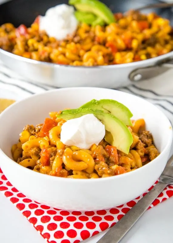 taco pasta skillet with avocado and sour cream in a white bowl