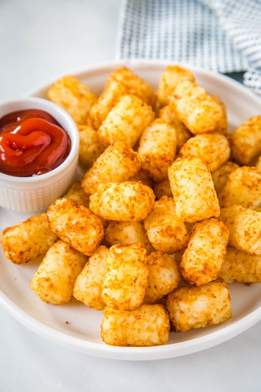 crispy tater tots on white plate with ketchup