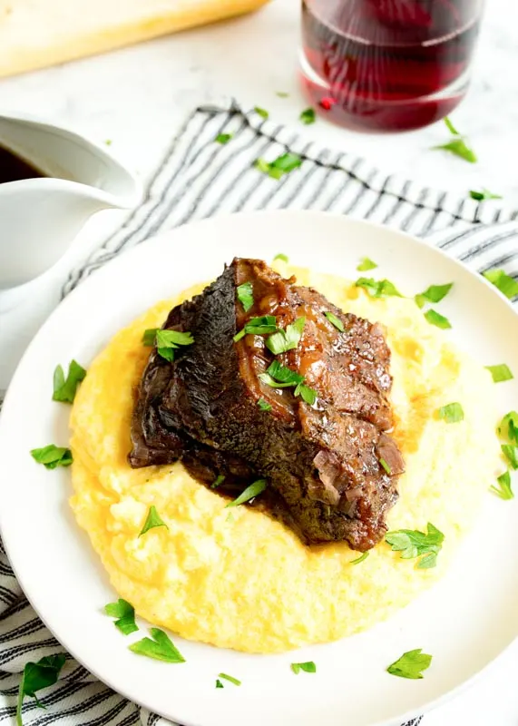braised beef short ribs over polenta on a plate