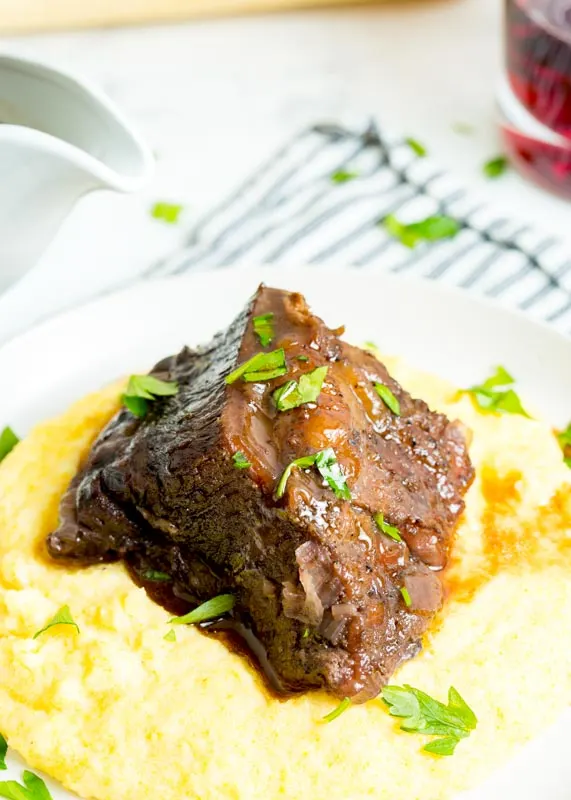polenta on a plate with beef rib over it