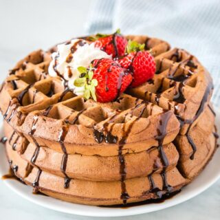 cropped photo of chocolate waffles with strawberries and chocolate sauce