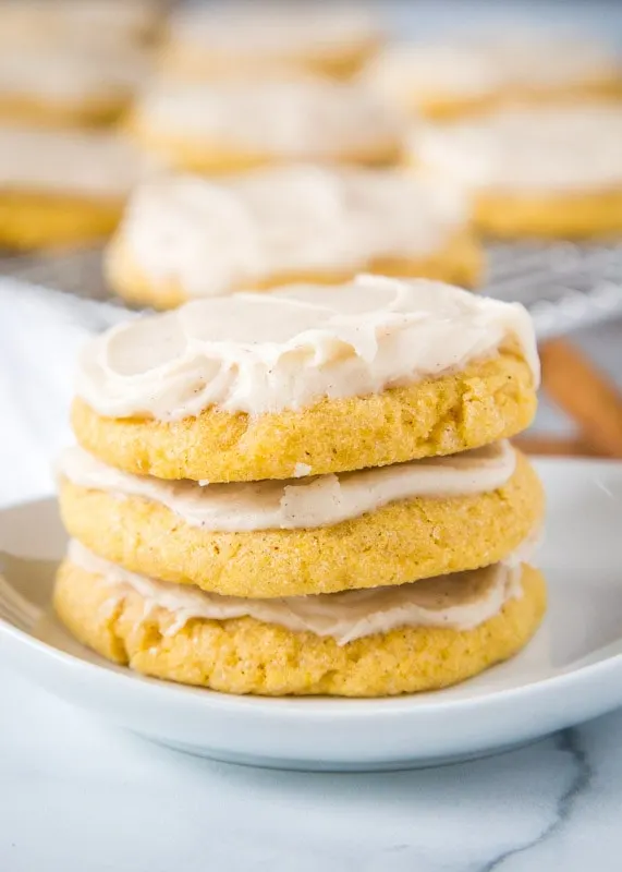 pumpkin sugar cookies stacked on white plate