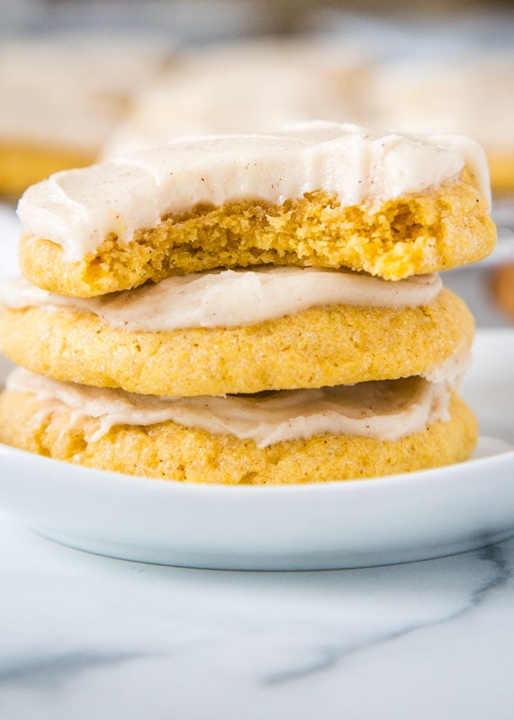 pumpkin sugar cookies stacked with top cookie missing a bite