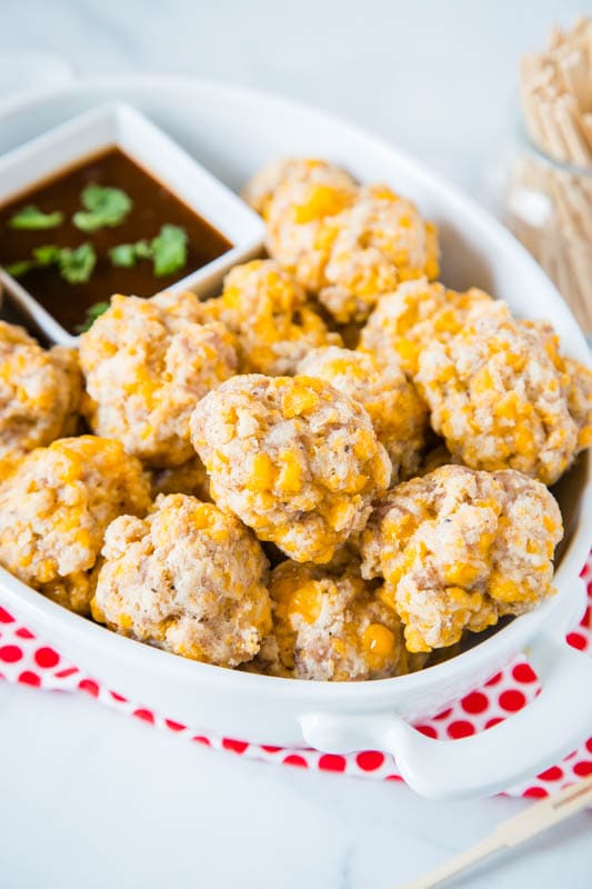 cheesy sausage balls in white dish with barbecue sauce
