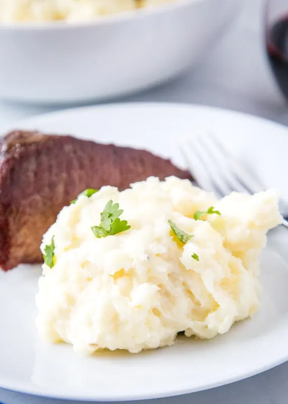 scoop of mashed potatoes on a plate with steak