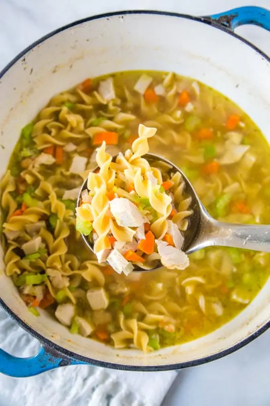 turkey soup in a pot with a ladle scooping out soup