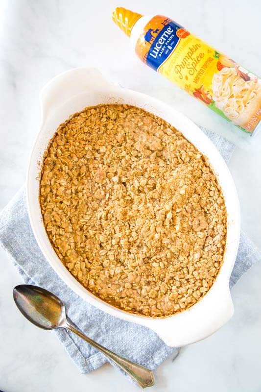 looking down on dish of pumpkin crisp with spoon and canister of whipped cream