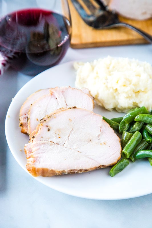 sliced turkey on plate with potatoes and green beans