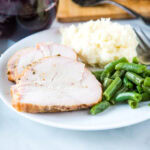 close up sliced turkey breast on plate with potatoes and beans