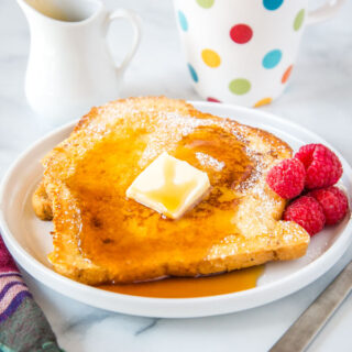 cropped picture of french toast on plate with butter and syrup