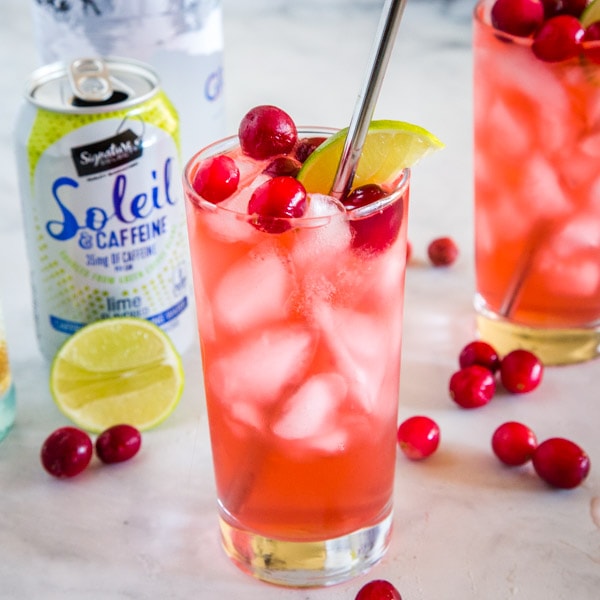 cropped image of cranberry spritzer in glass with fresh cranberries on top