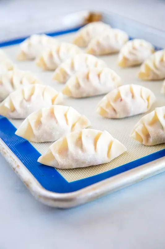 folding dumplings on a baking tray