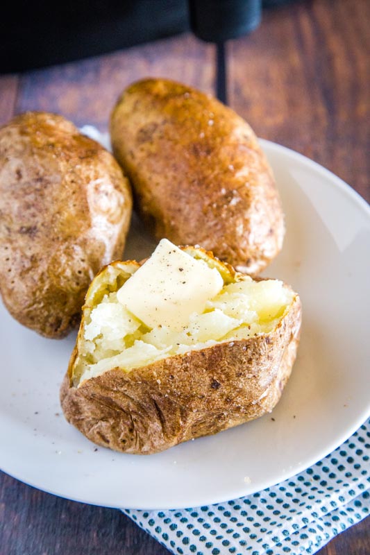baked potato cut open with butter in a plate