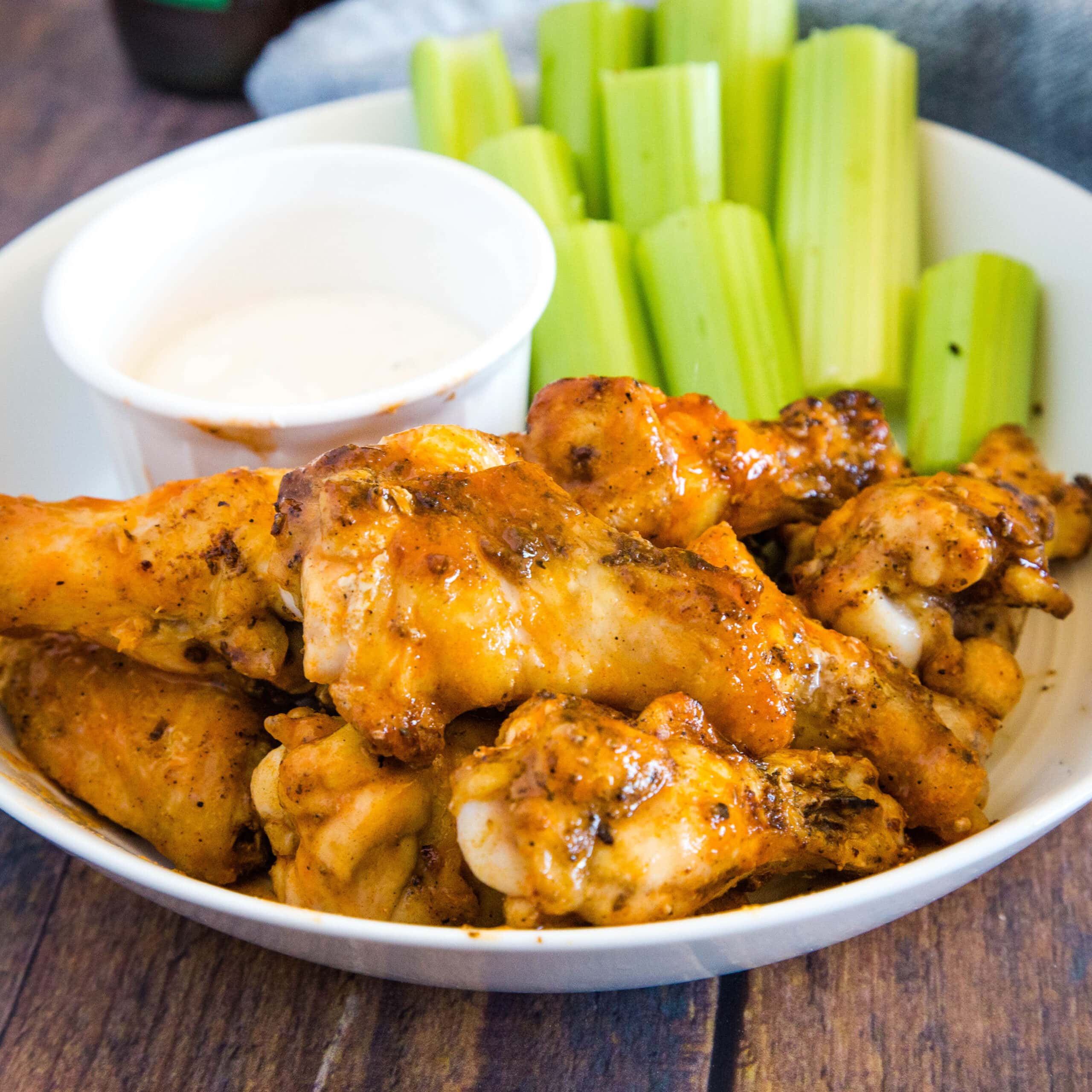cropped image of buffalo chicken wings on plate with ranch and celery sticks