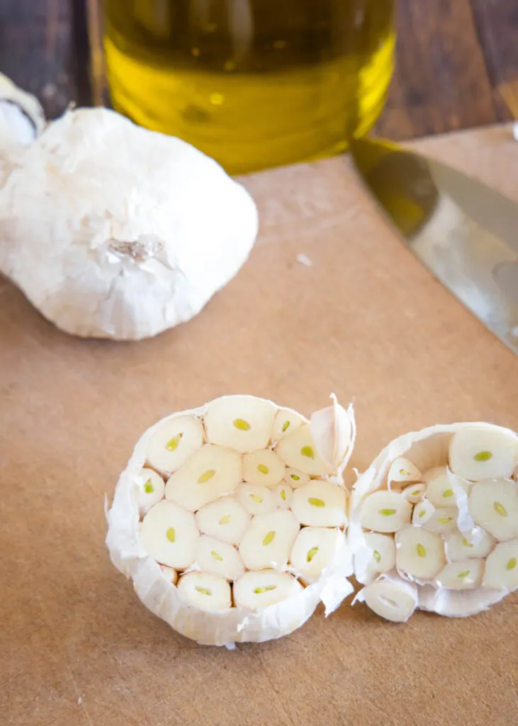 raw head of garlic on cutting baord