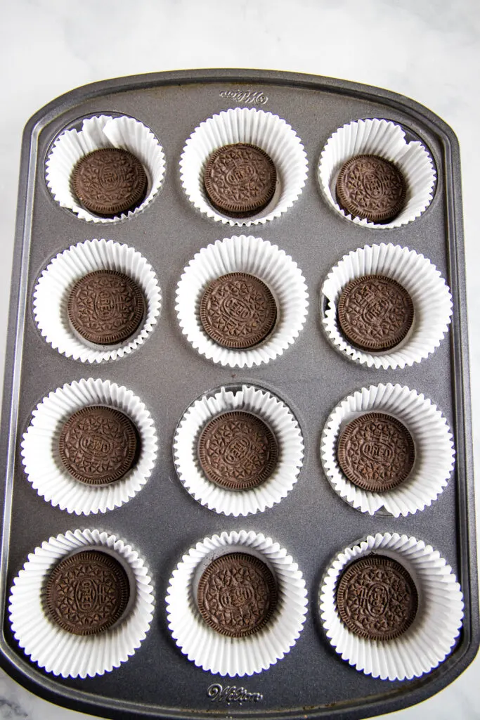 muffin tin lined with paper liners and an oreo in each cup