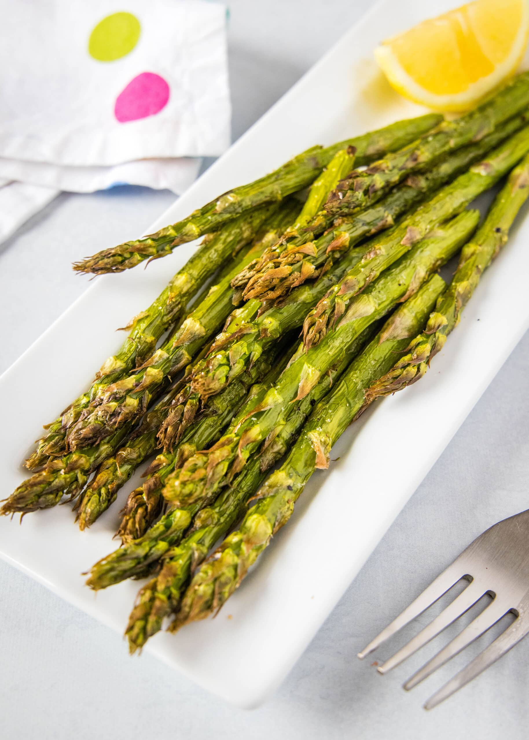 air fryer asparagus on plate with a fork and lemon slice