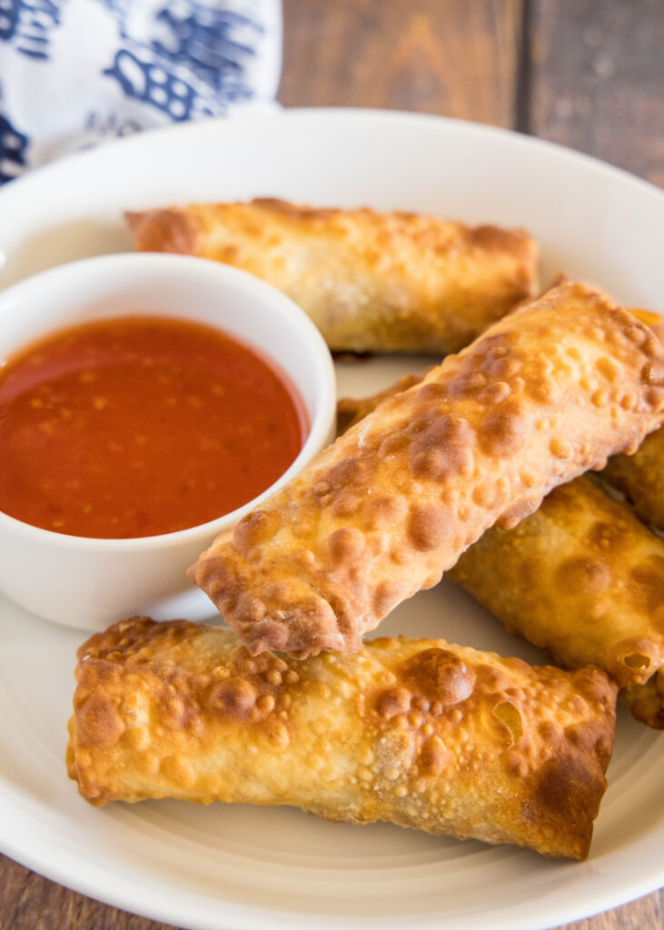 cooked egg rolls on a plate with dipping sauce