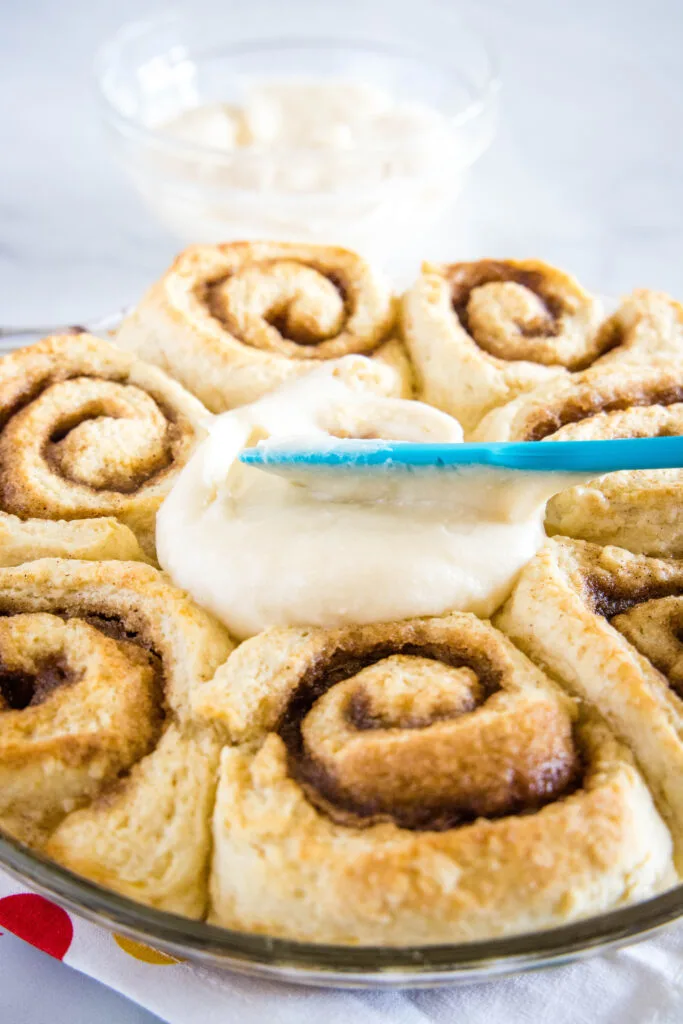 spreading frosting on cinnamon rolls