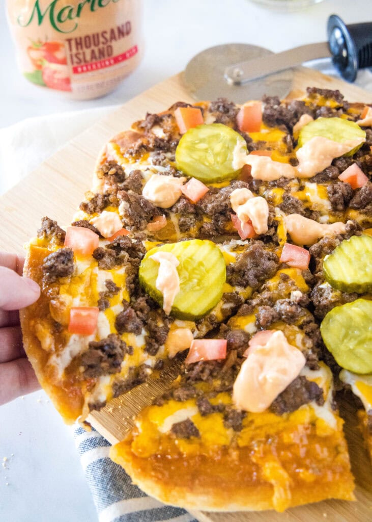 pizza on a cutting board with a slice being picked up