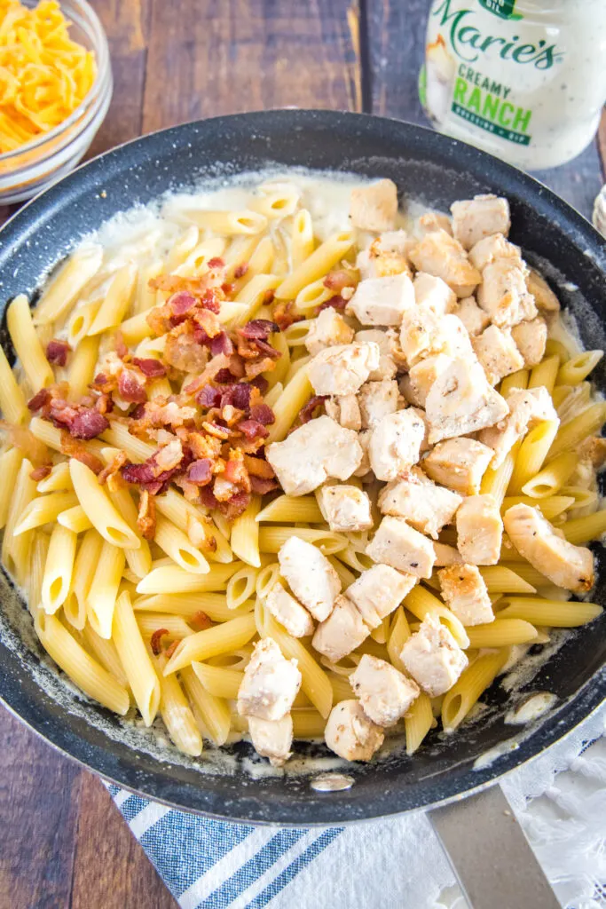 adding chicken, pasta, and bacon back to the ranch sauce in the pan