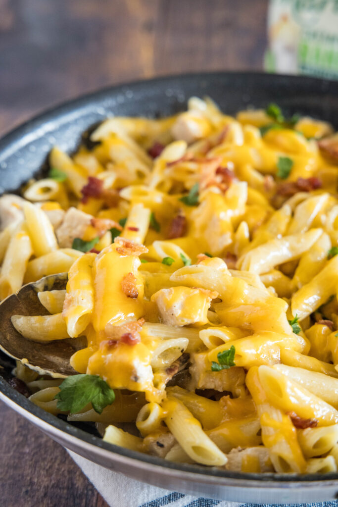 spooning cheesy ranch pasta out of skillet