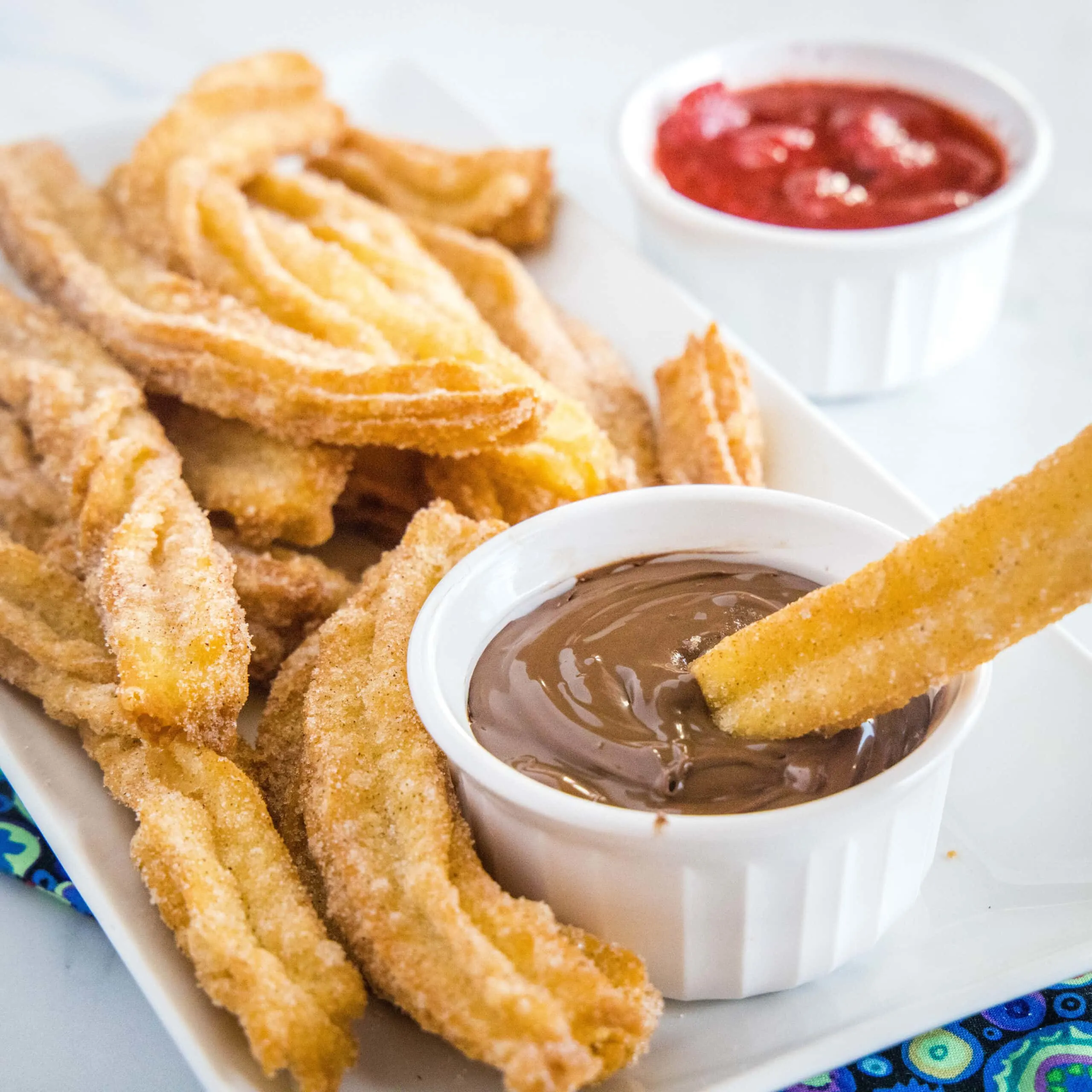 close up of churros on a plate being dipped in chocolate