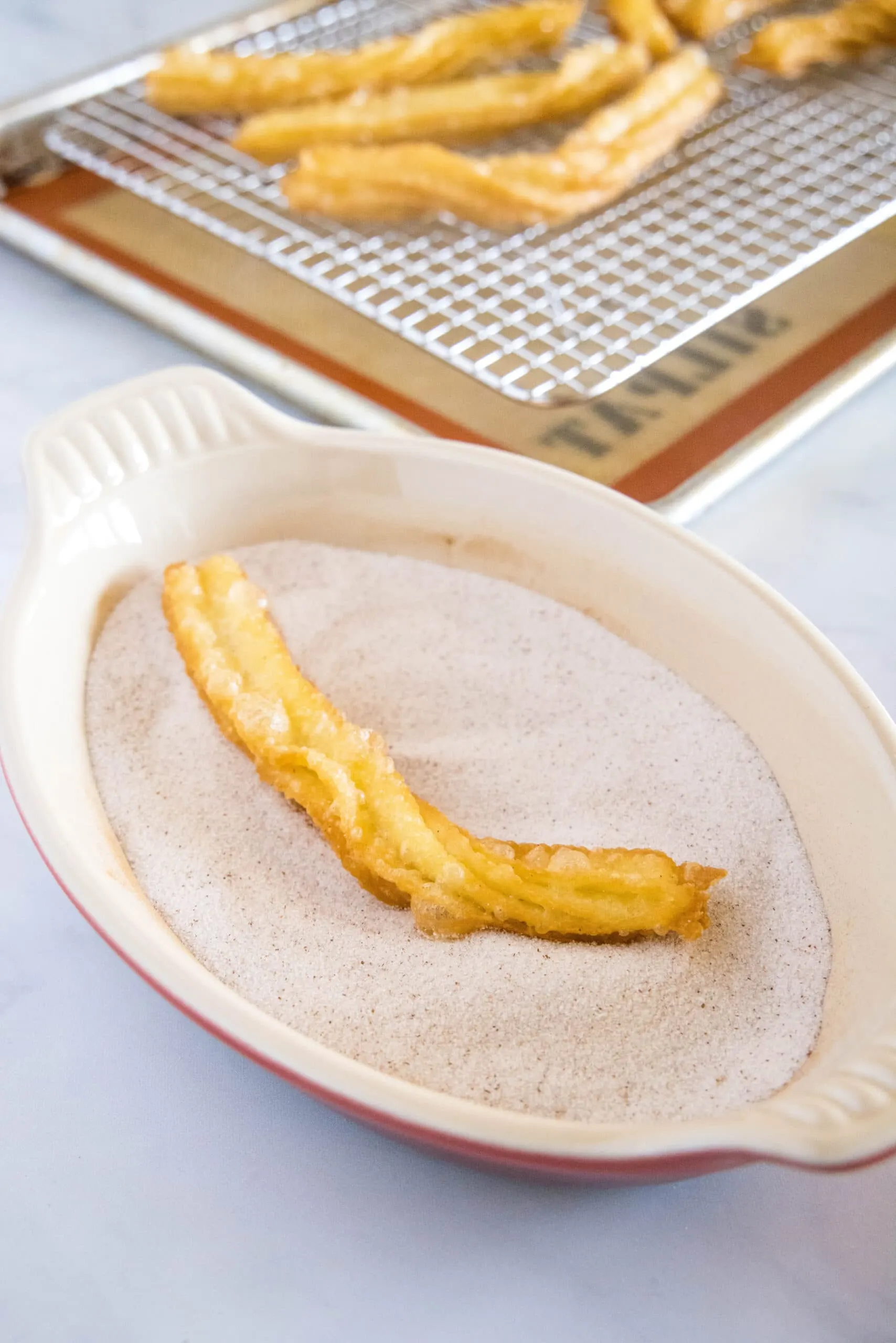 fried churro being tossed in cinnamon sugar
