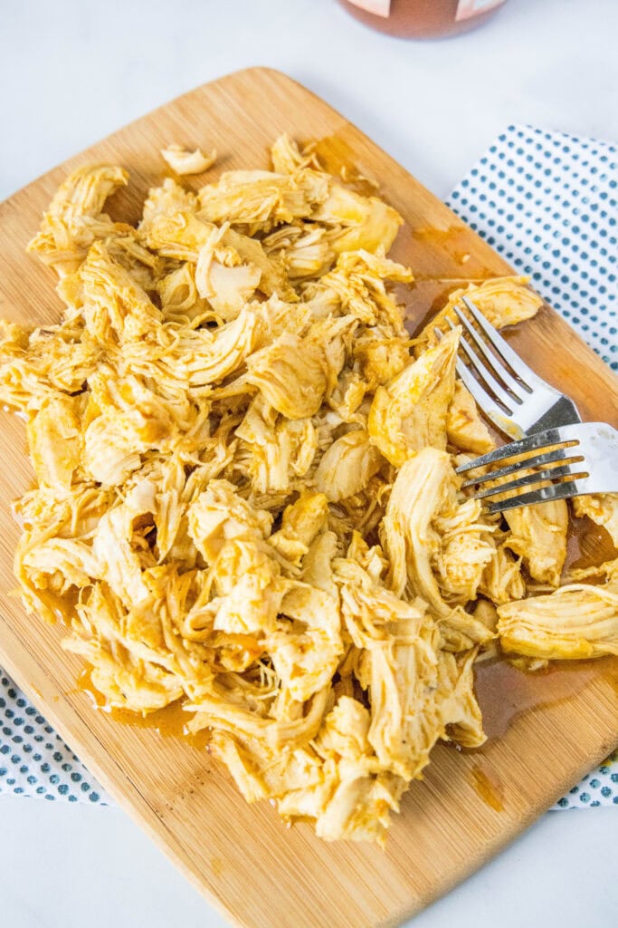 looking down on shredded chicken on a cutting board