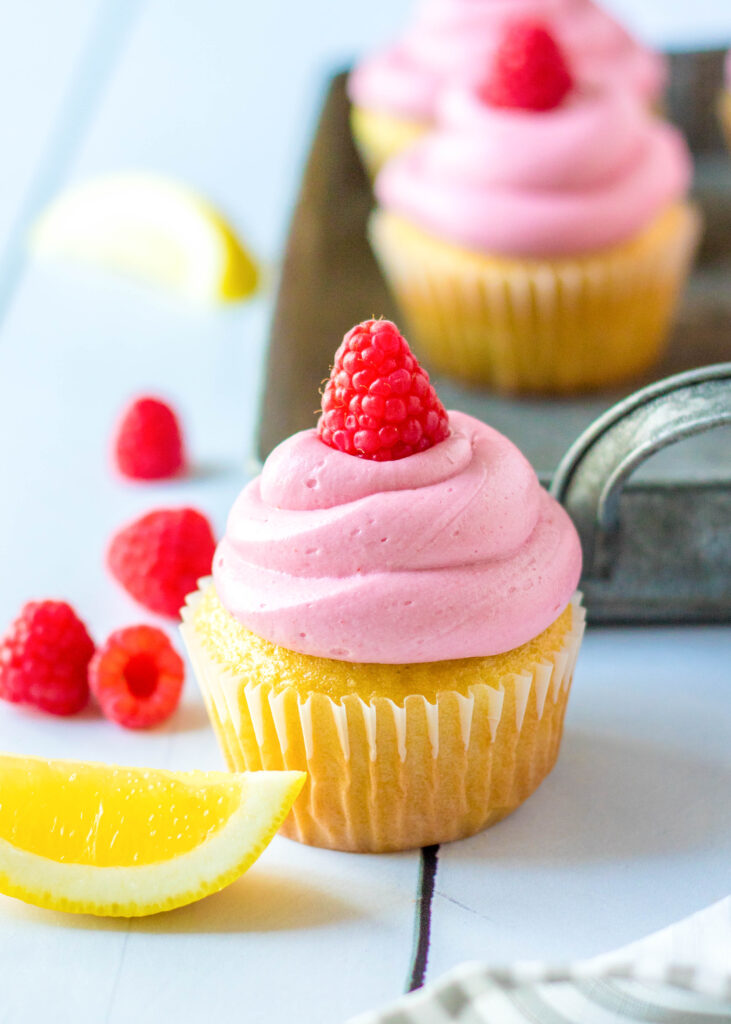 lemon cupcakes with raspberry frosting with a slice of lemon next to it