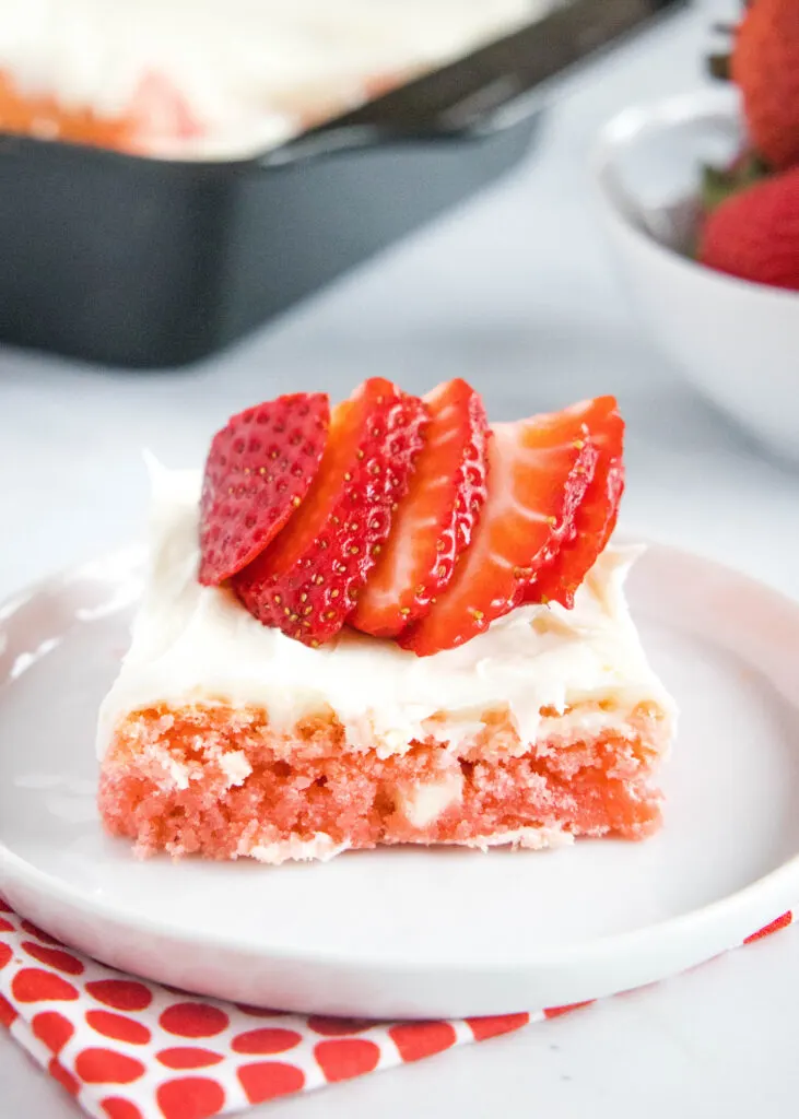 strawberry frosted brownie on a plate topped with strawberries