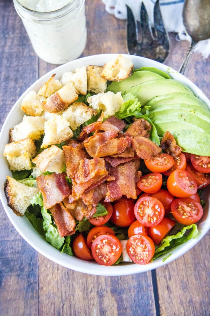 looking down on bowl with bacon, lettuce, tomato, croutons and avocado