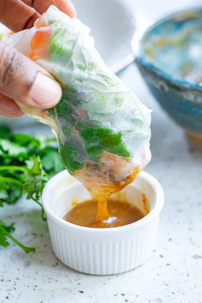 dipping a summer roll in peanut sauce