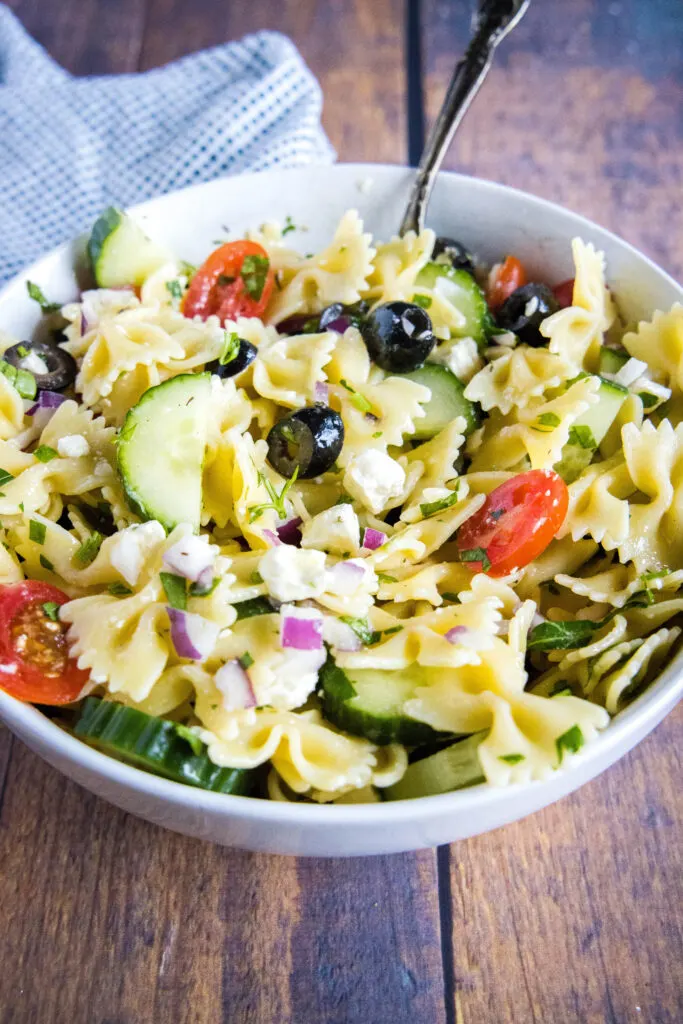 greek pasta salad tossed together in a bowl