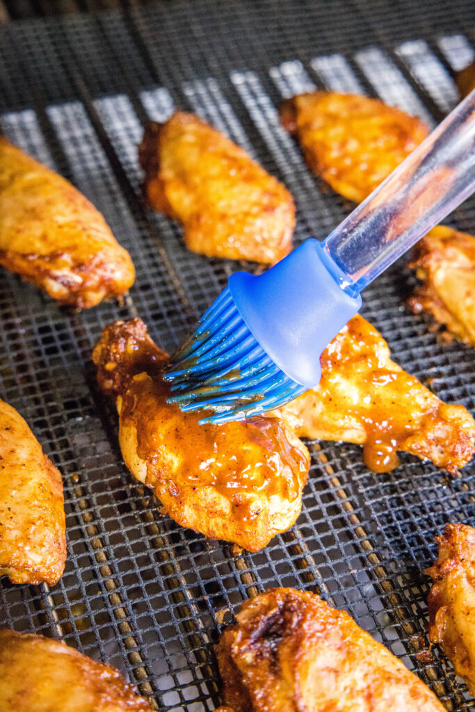 brushing barbecue sauce on chicken wings