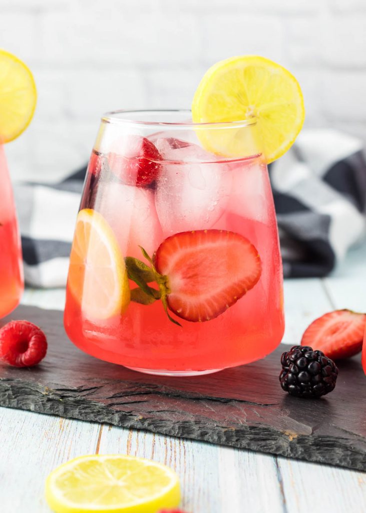 glass of sparkling lemonade with berries and a slice of lemon