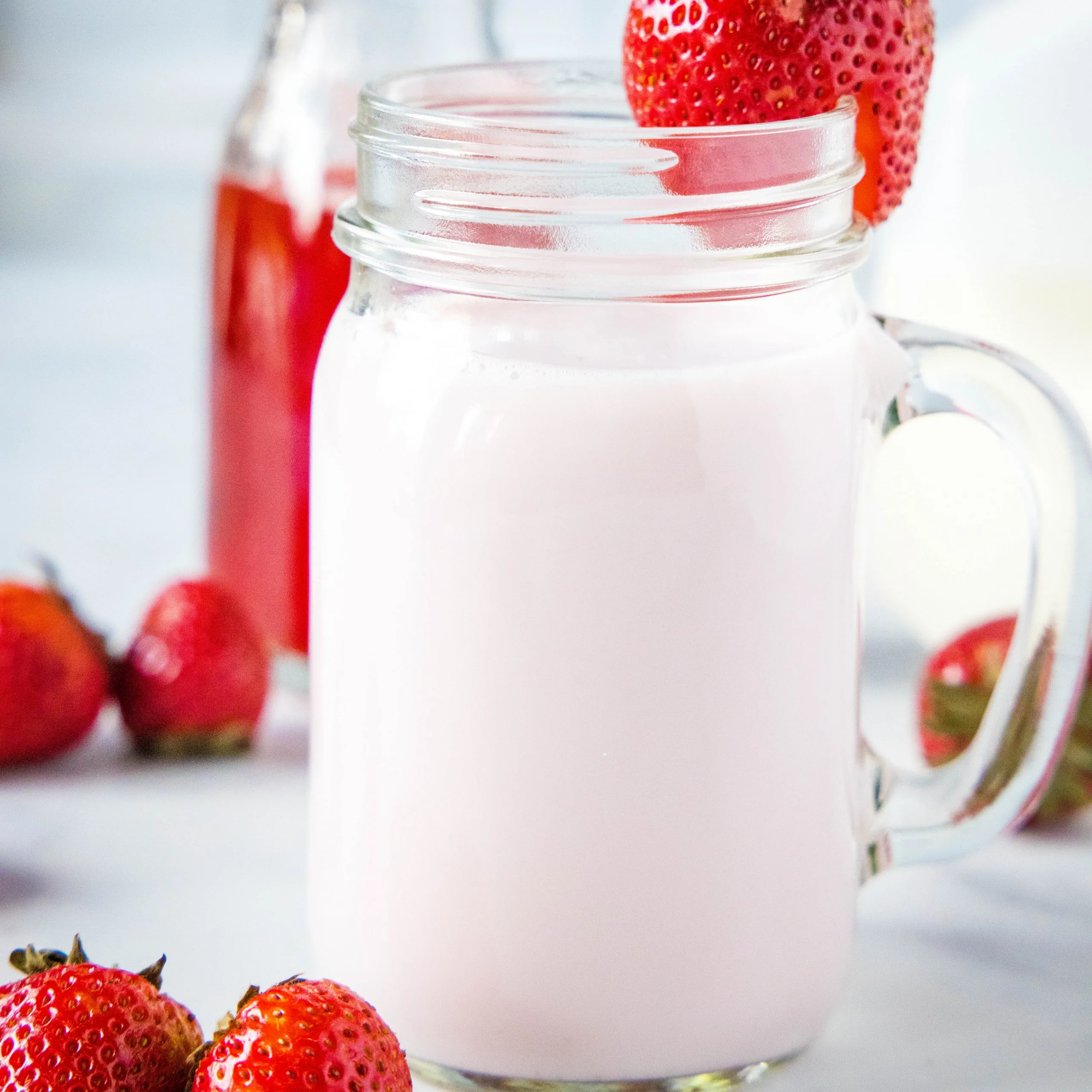 close up of strawberry milk with strawberry on rim of glass