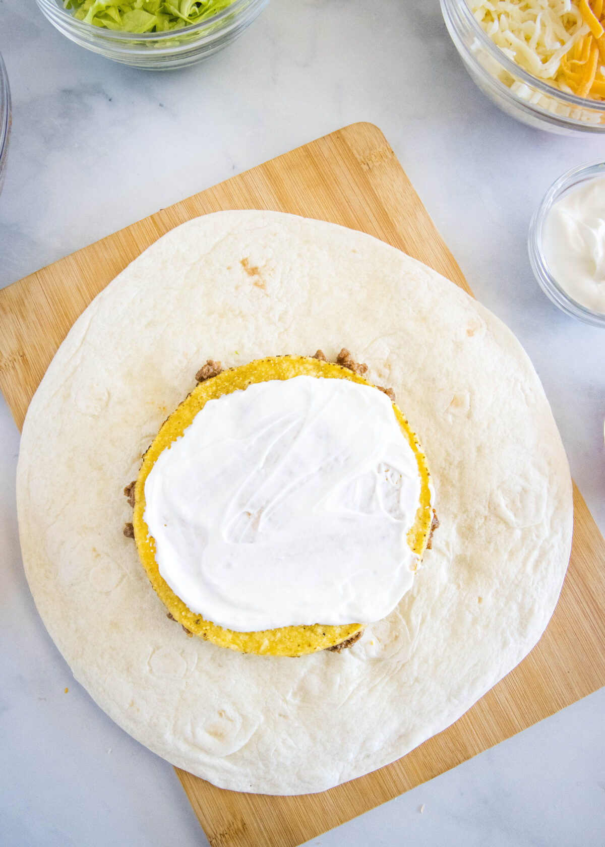 adding sour cream to a tostada shell