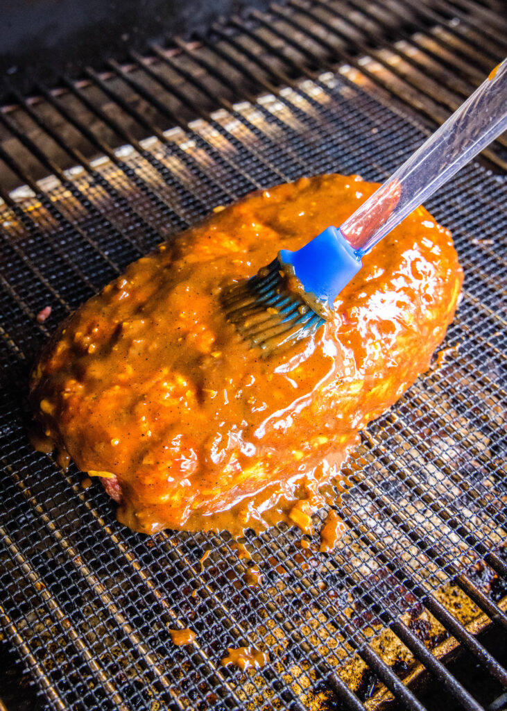 brushing barbecue sauce on meatloaf