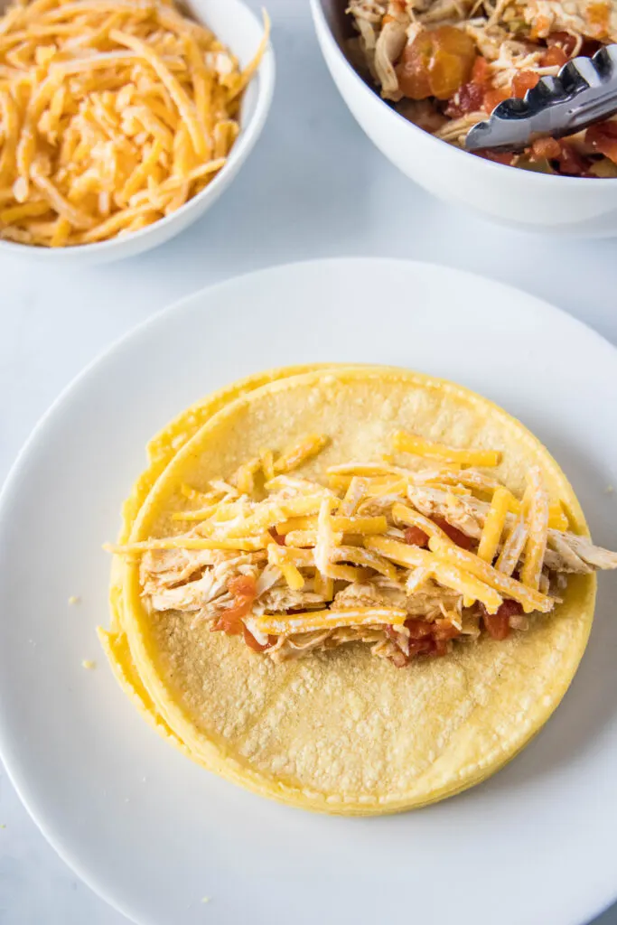 filling corn tortillas with chicken and cheese