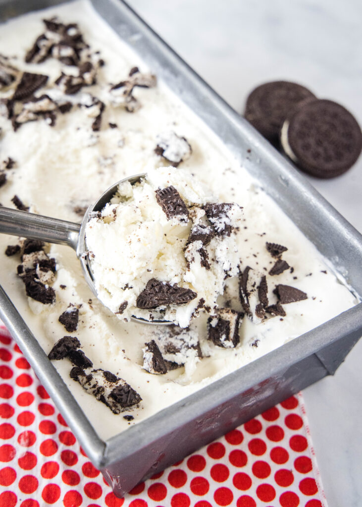 scooping cookies and cream ice cream out of a pan