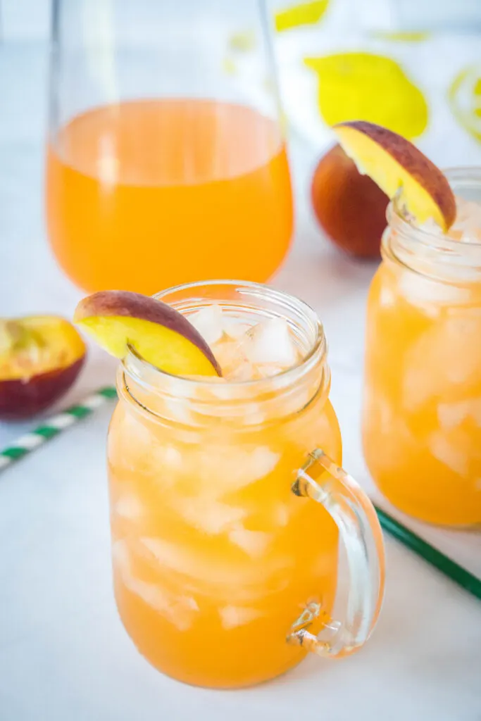 peach lemonade in glasses with ice on a table