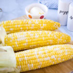 close up of smoked corn on the cob on a cutting board