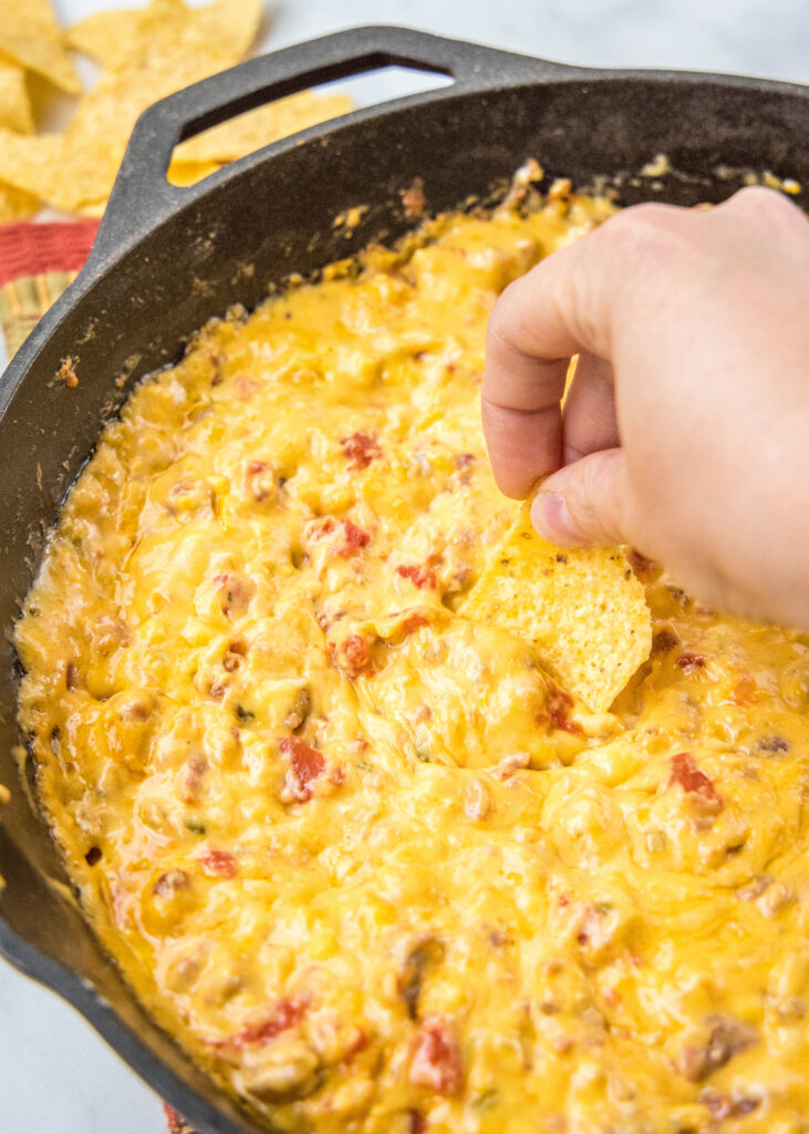 dipping a chip in queso dip