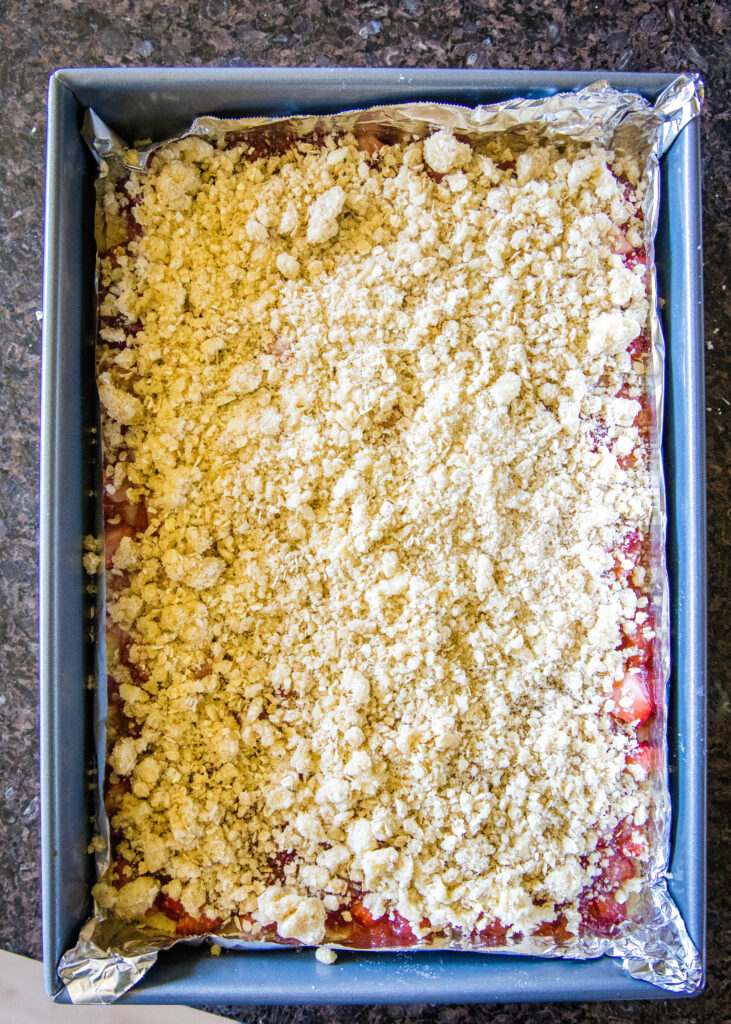 adding crumb topping to strawberry bars