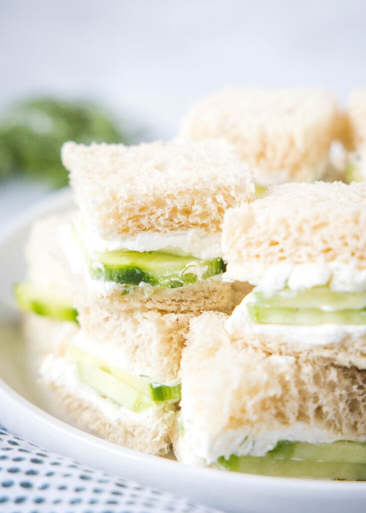 a stack of tea sandwiches on a white plate