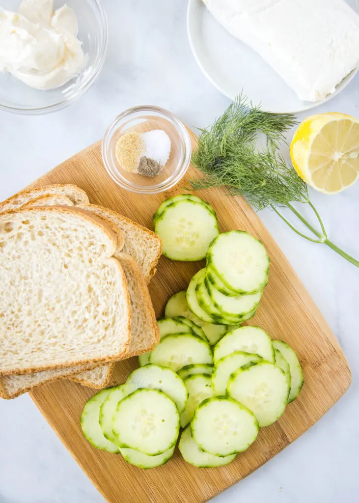 a cutting board with ingredients to make cucumber sandwiches