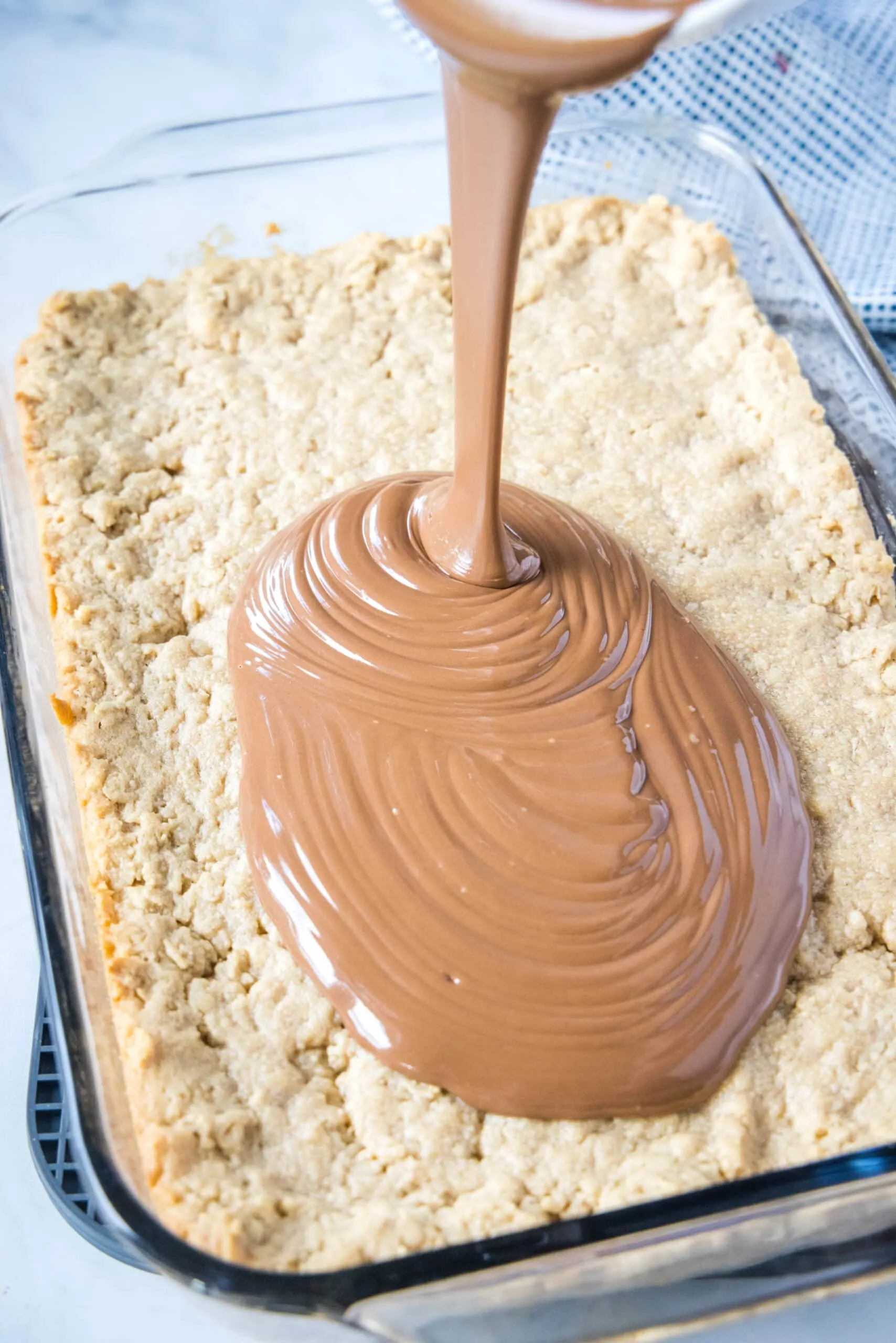 pouring chocolate over peanut butter bars